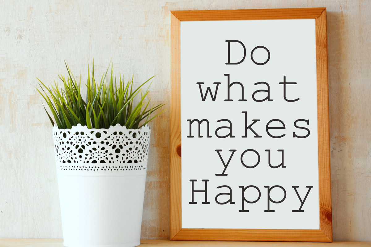 A framed sign that says "Do What Makes You Happy" on a wooden counter top next to a potted succulent