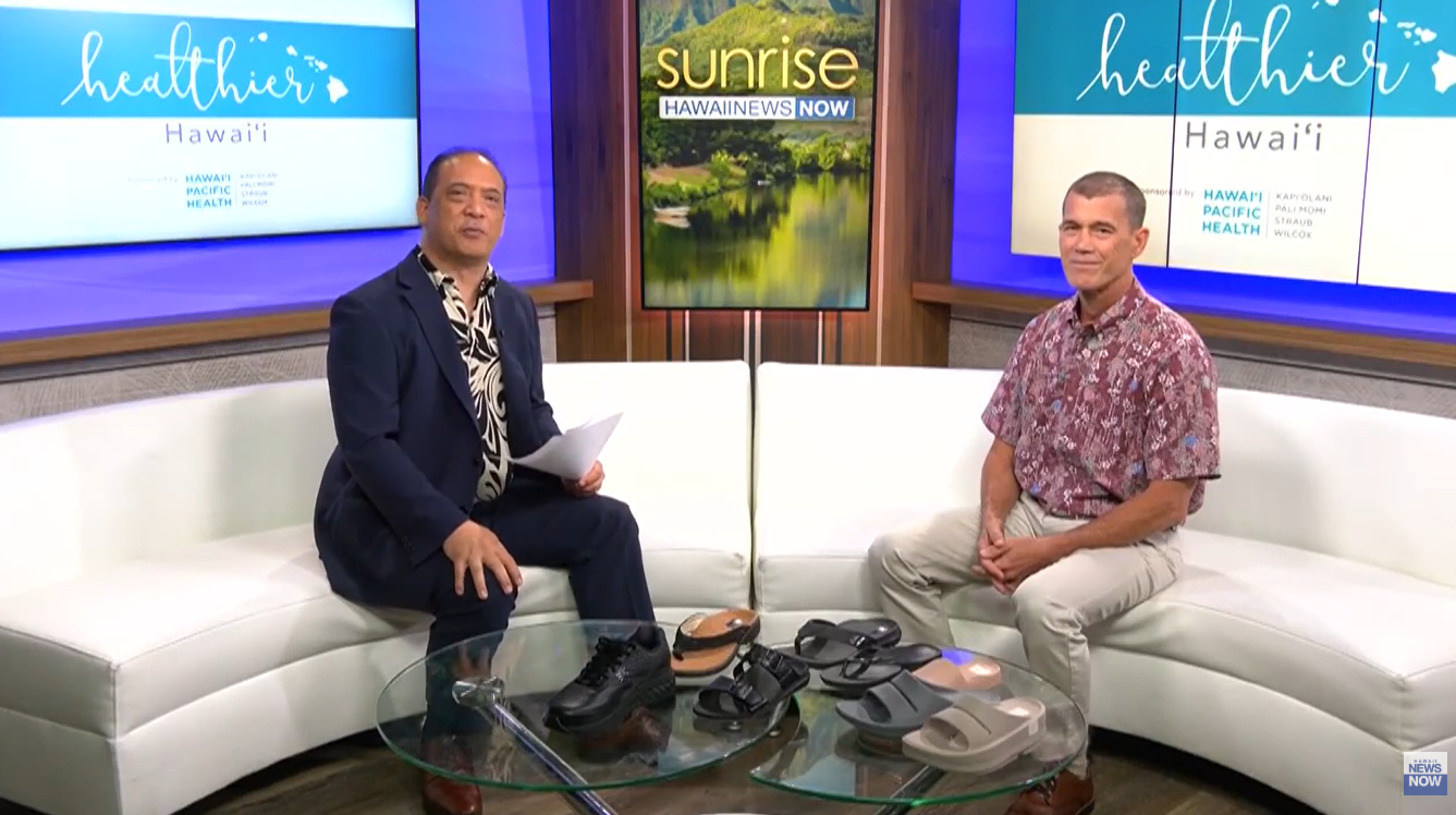 Morning news set with anchor and Dr. Chihara sitting on white couches with healthier Hawaii signage on monitors behind them. 