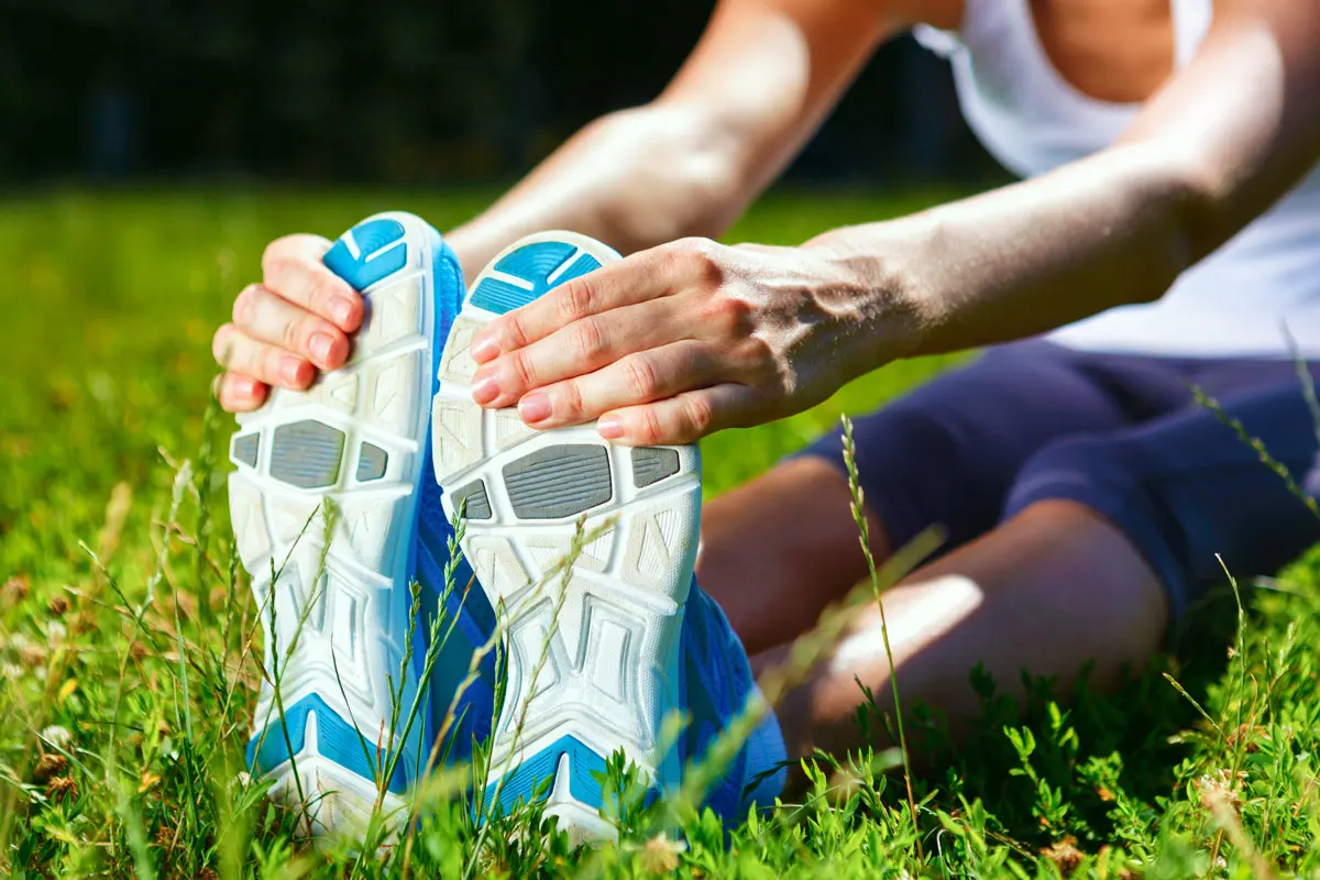 A runner stretching in a grassy field.