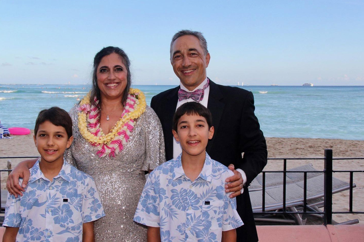 Honoree standing on the beach with her family, smiling with her husband and their two sons.