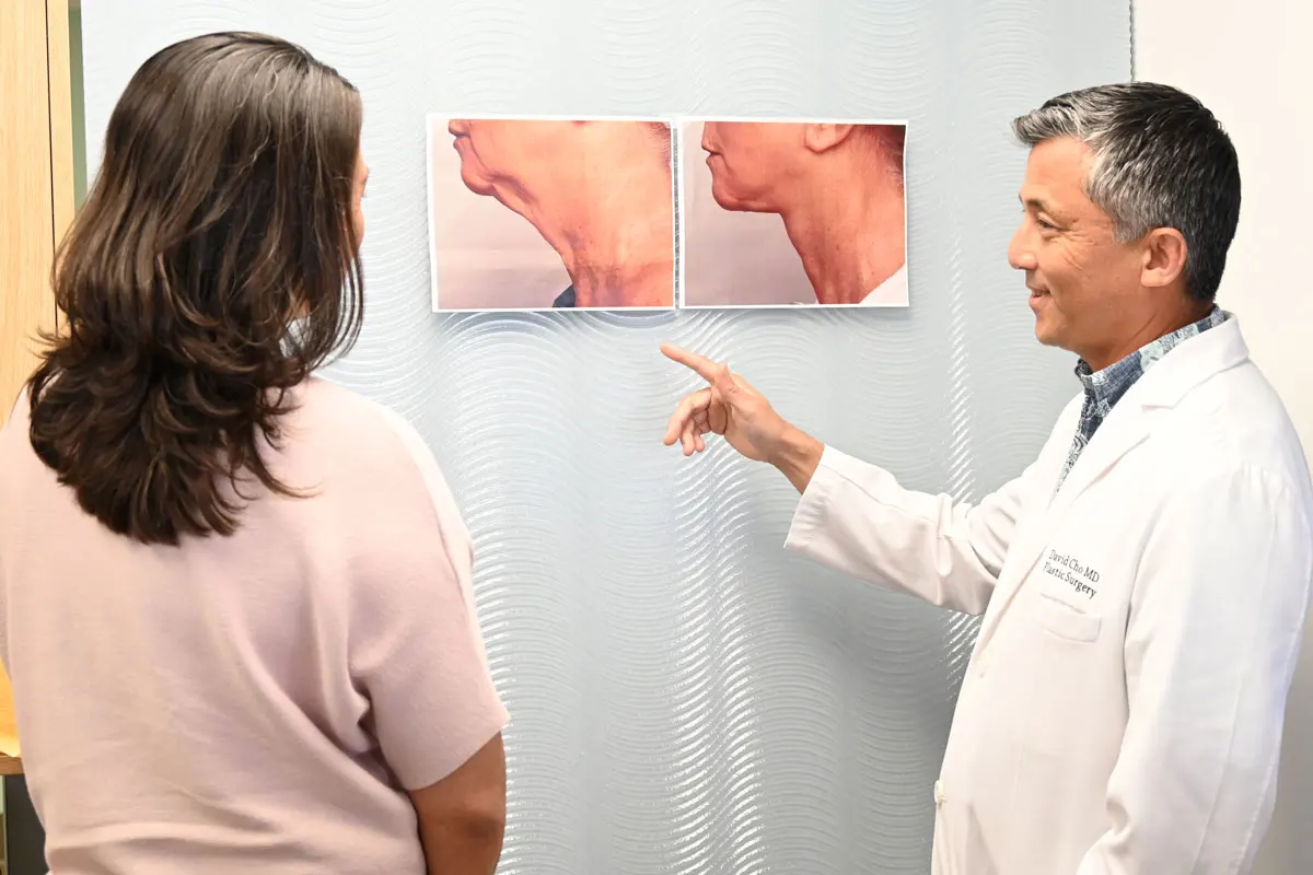A plastic surgeon and department supervisor look at before-and-after photos of a patient's facelift.