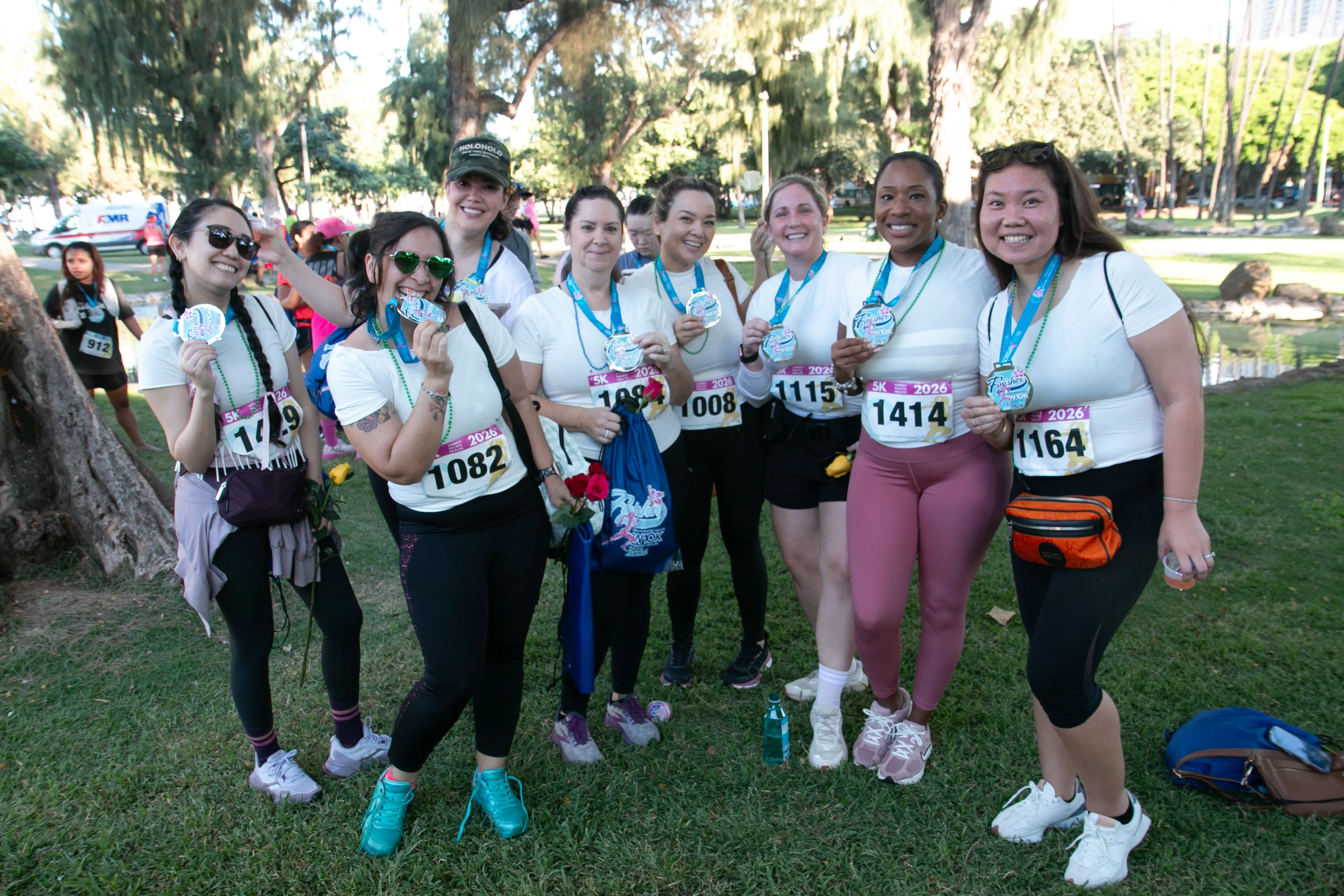 Group of 5K participants wearing matching tops smiling and posing with their finisher medals.