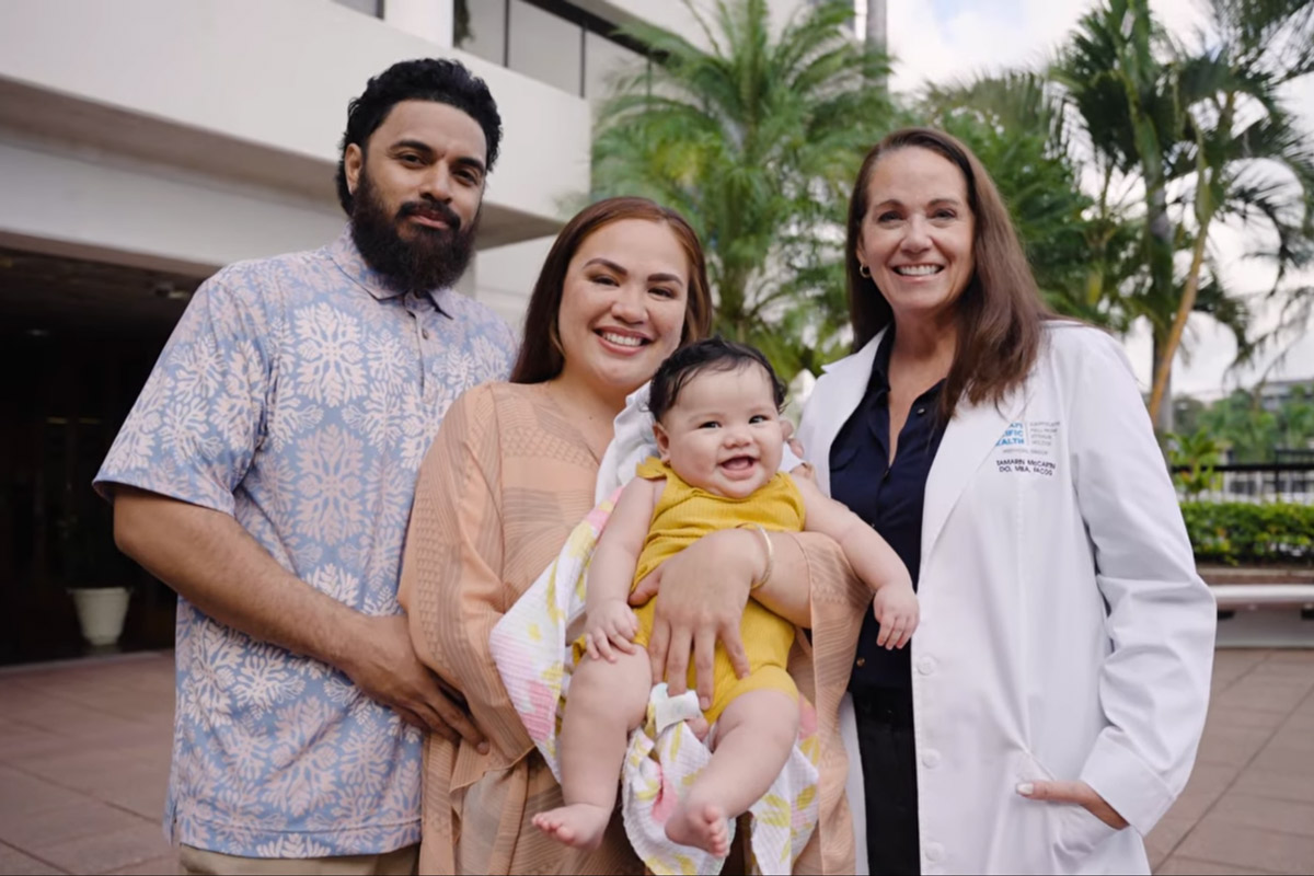 Physician smiling with a mom and dad and their baby. 
