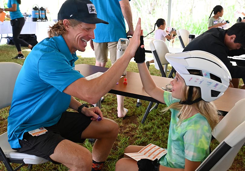 Doctor high fives a young kid he's just fitted with a bicycle helmet.