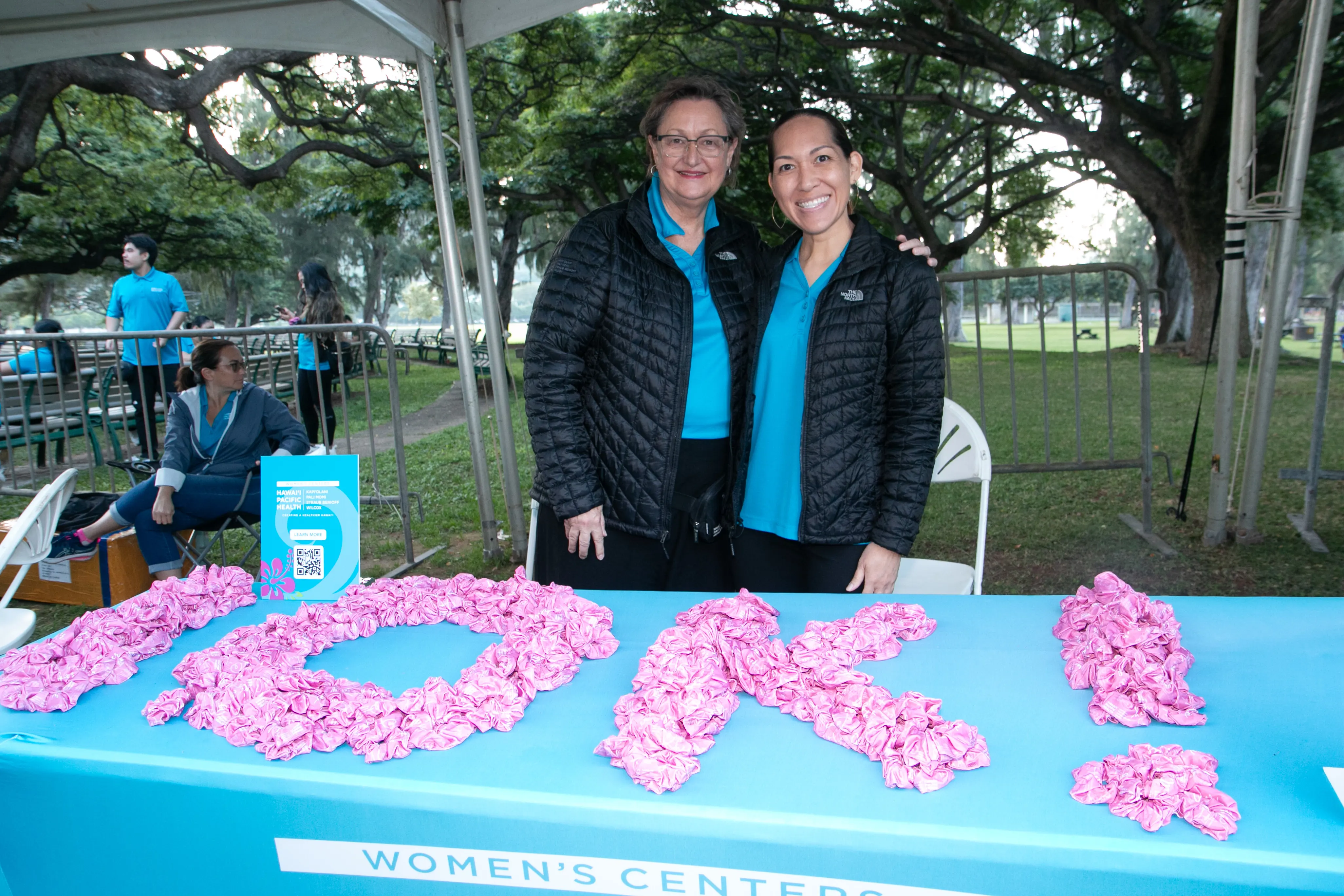 HPH volunteers smiling with a 10K sign made out of pink scrunchies.