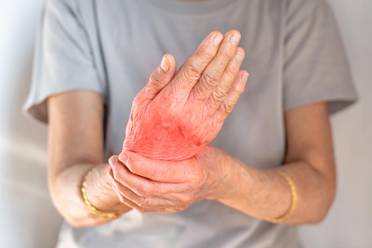 An elderly woman holds her wrist in pain.