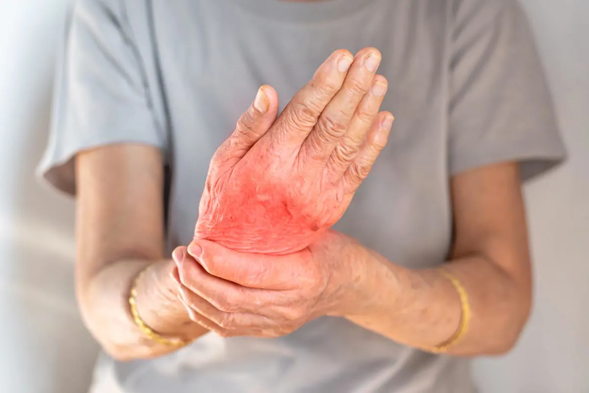 An elderly woman holds her wrist in pain.