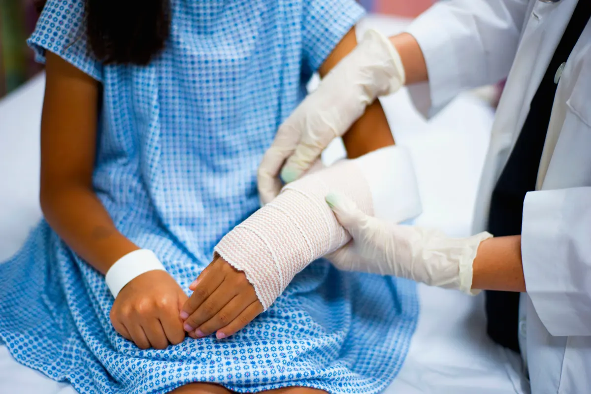 A young girl getting a cast applied by a doctor.