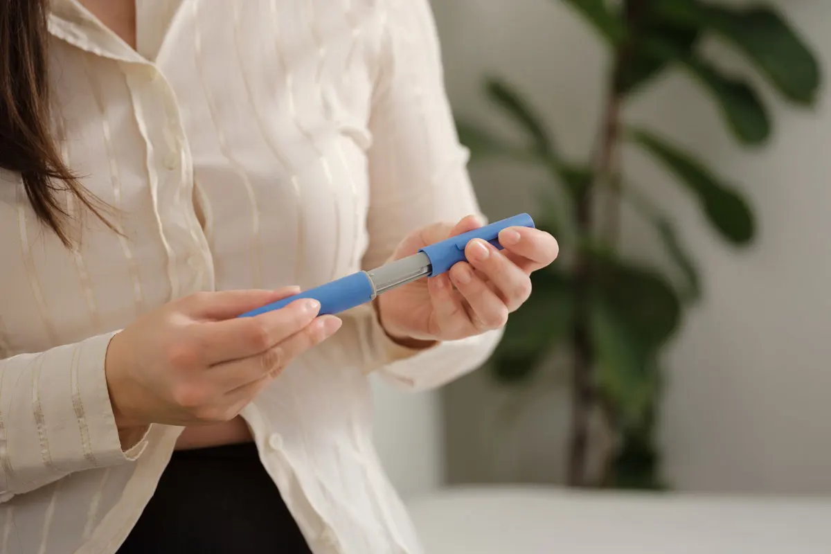 Person holding an injector for peptides.