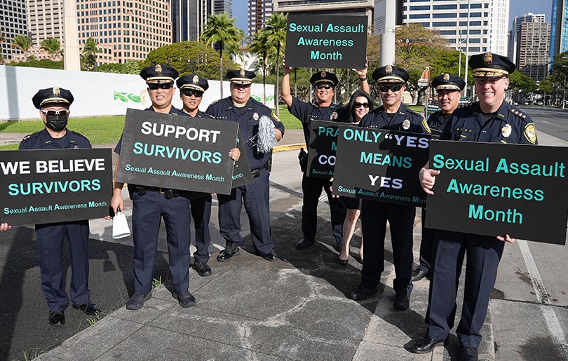 Honolulu Police Department officers holding signs in support of survivors of sexual assault.