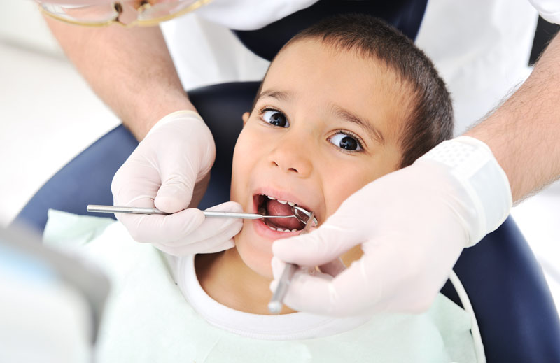 A young child with dental tools in the mouth.