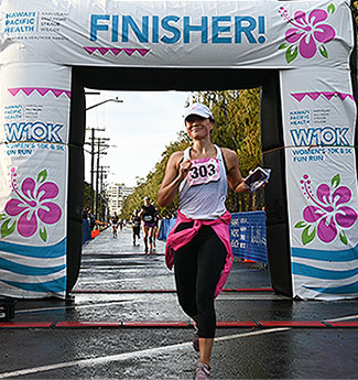 Female runner coming through the finish line arch. 