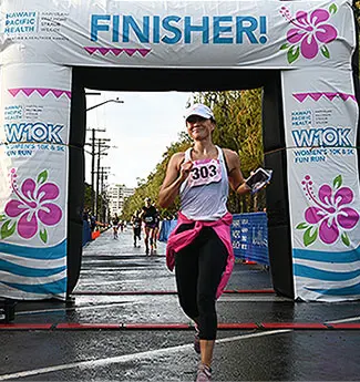 Female runner coming through the finish line arch. 