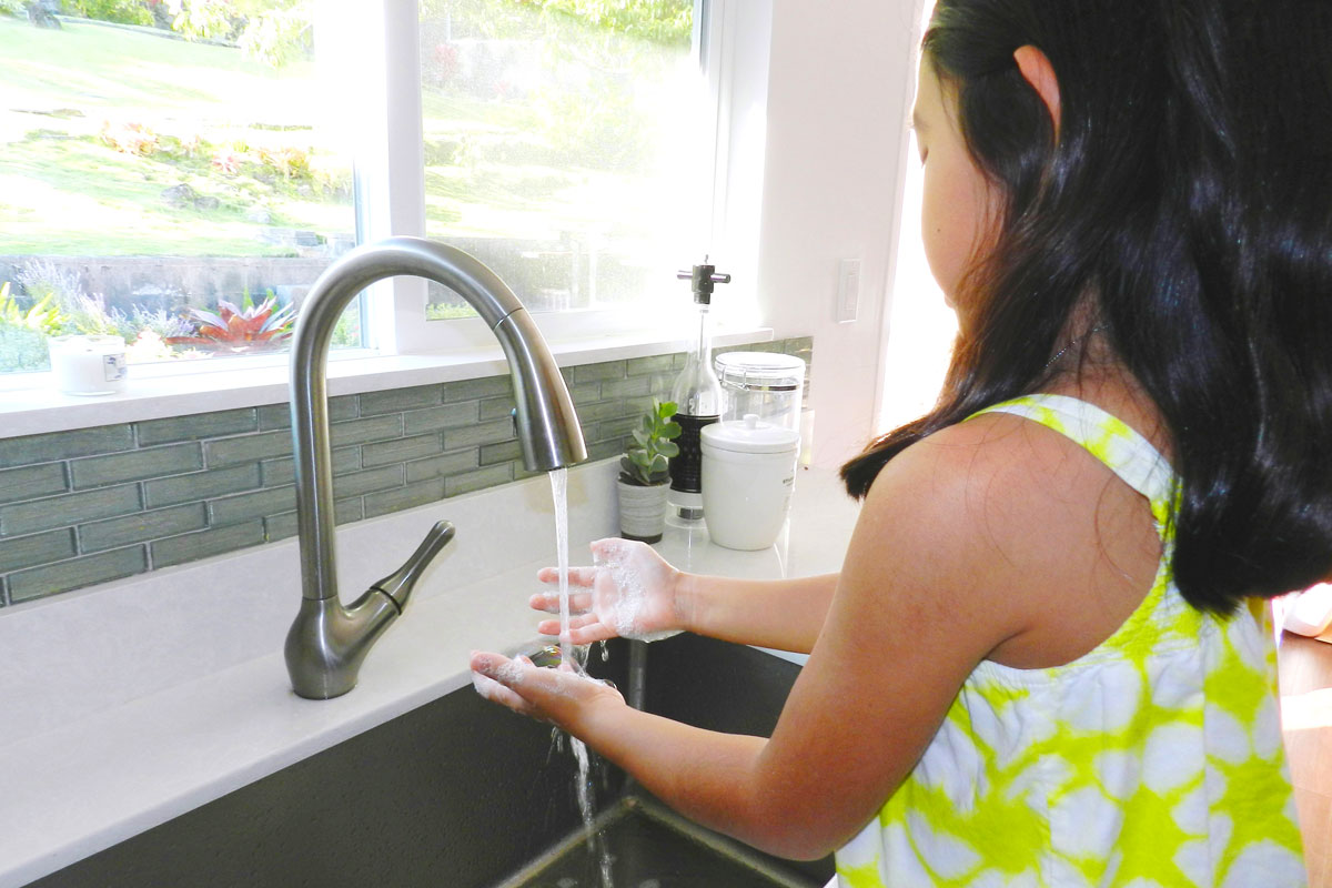 A girl washing hands in a sink.