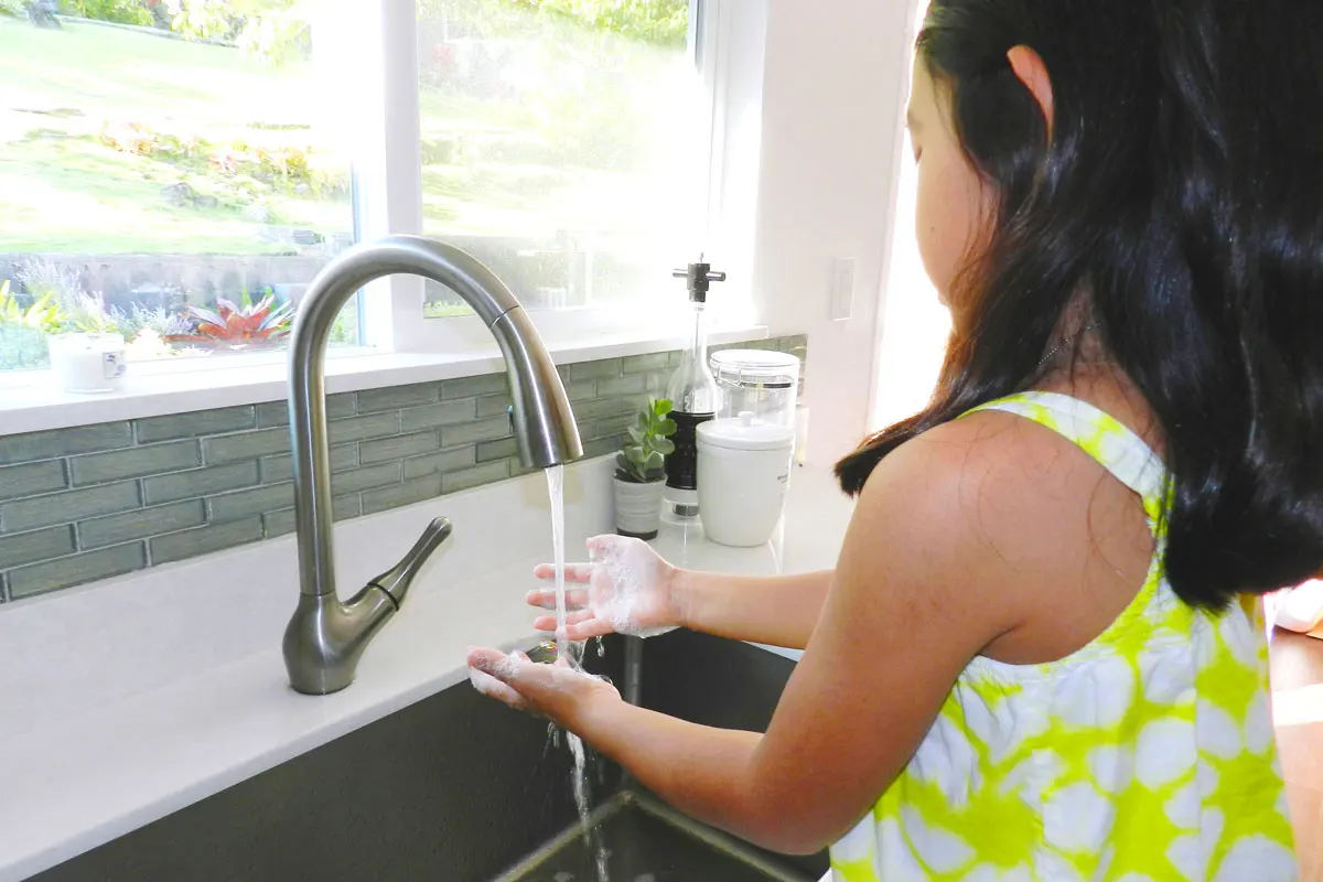 A girl washing hands in a sink.