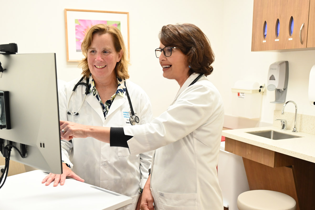Two physicians talking and looking at a screen.