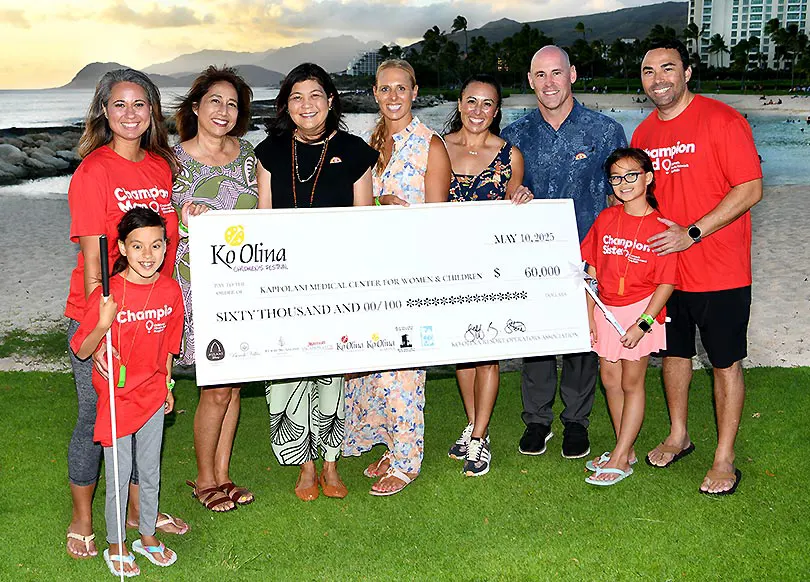 Group of nine people smiling with a giant check for $60,000.