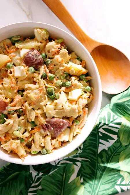 A bowl of Hawaiin-style potato salad with a wooden spoon.
