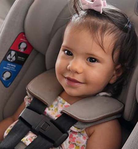 Baby girl smiling  while buckled safely in her car seat.