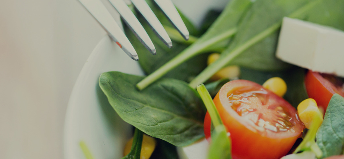 A bowl of salad with a fork.