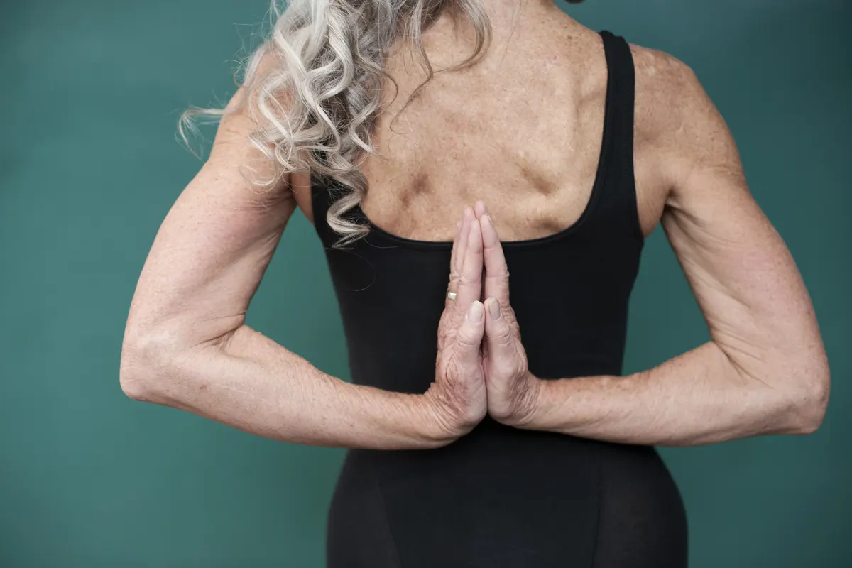 A woman's hands meet behind her back.
