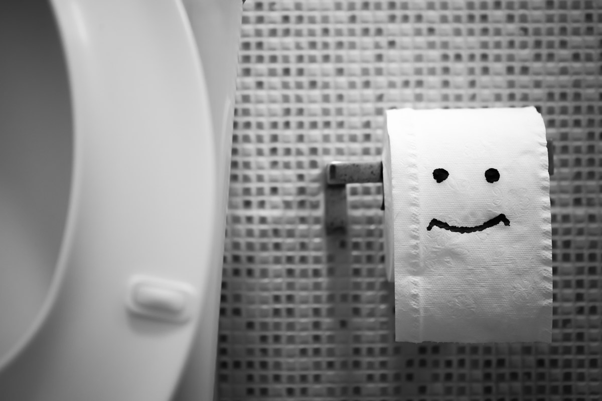 Close-up of a happy face drawn on a roll of toilet paper.