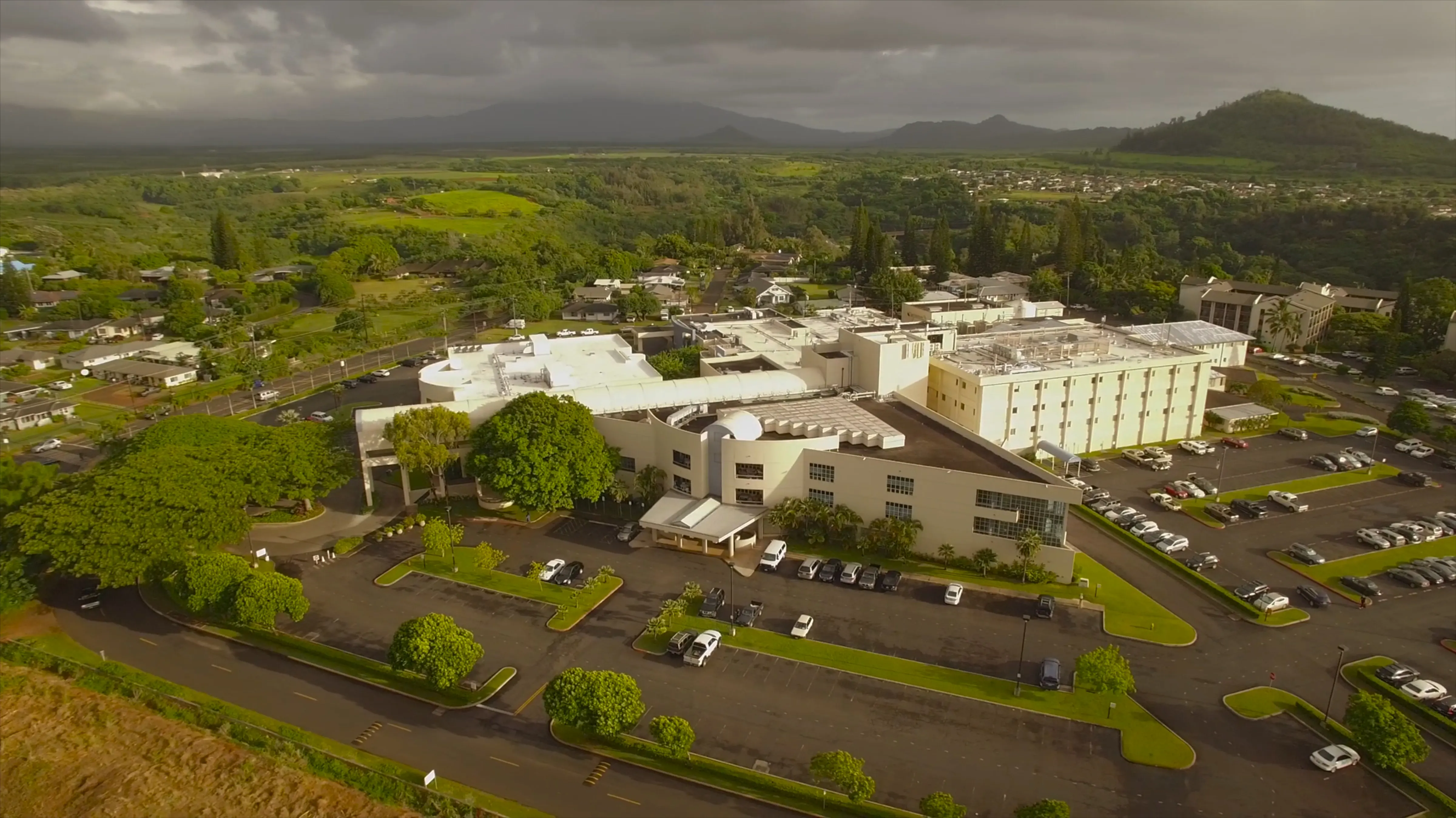 Aerial view of Wilcox Medical Center and Kauai Medical Clinic in Lihue with lush green landscape and mountains.
