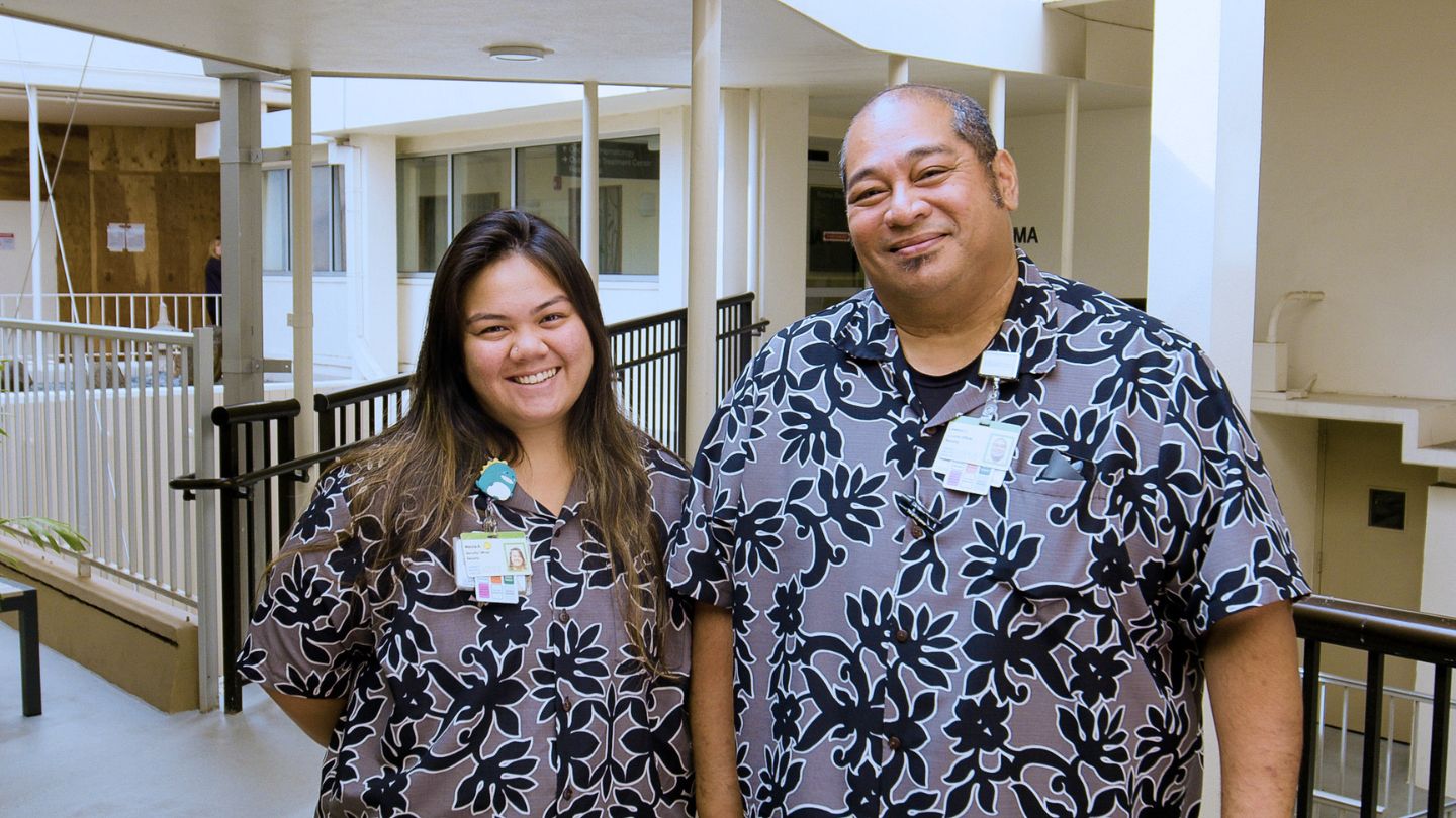 Two healthcare employees stand together in a hospital corridor.