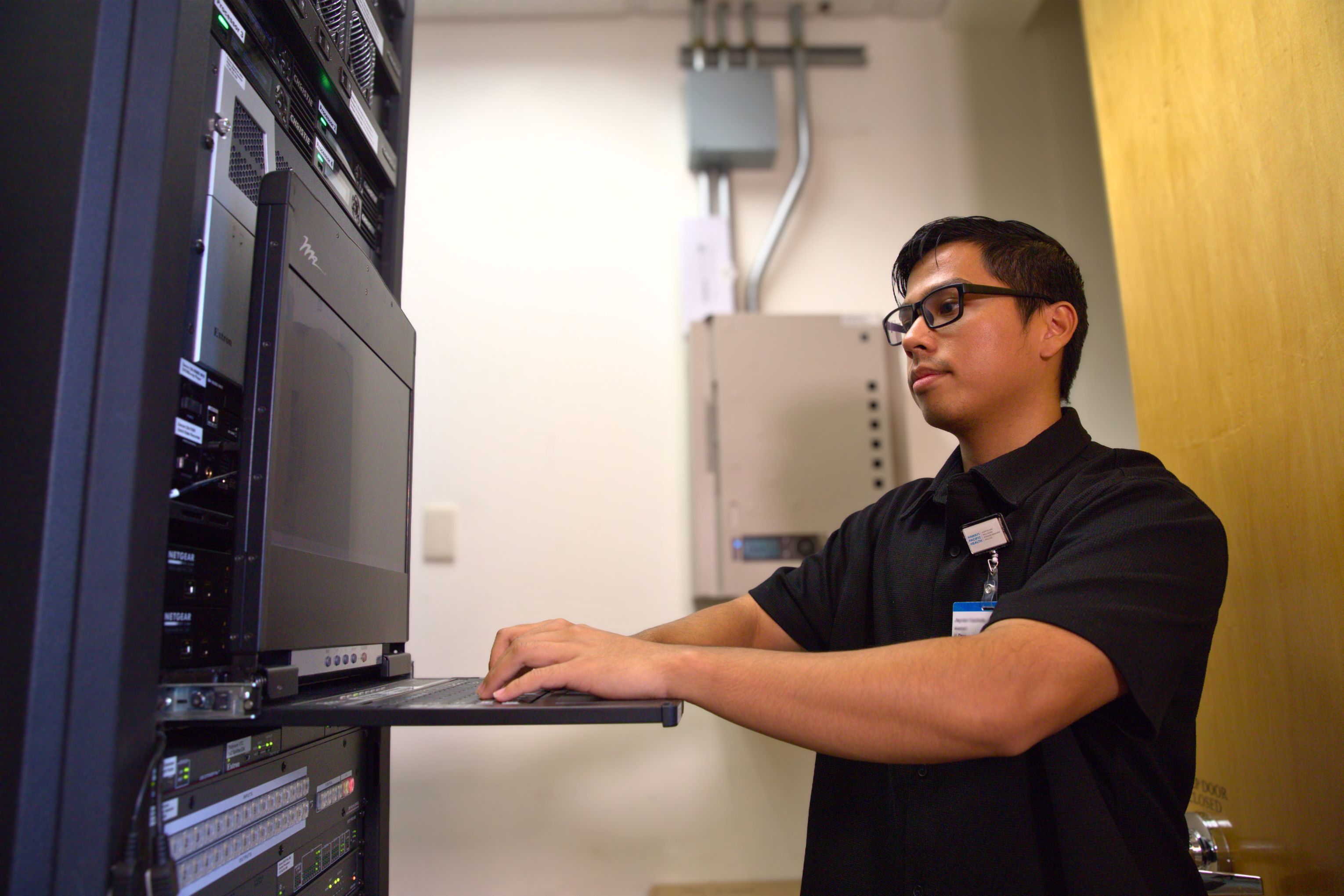 IT employee works on a laptop inside a server room
