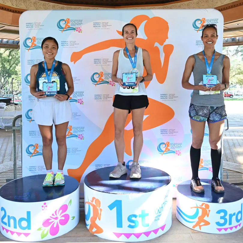 HPH Women's 10K top three finishers standing on winner podiums.