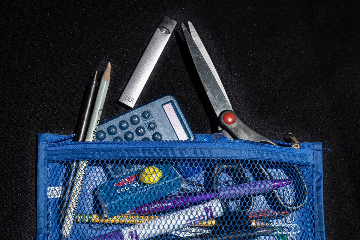 School items and a JUUL e-cigarette spilling out of a mesh bag.