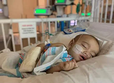 Akamu sleeps in a hospital bed.