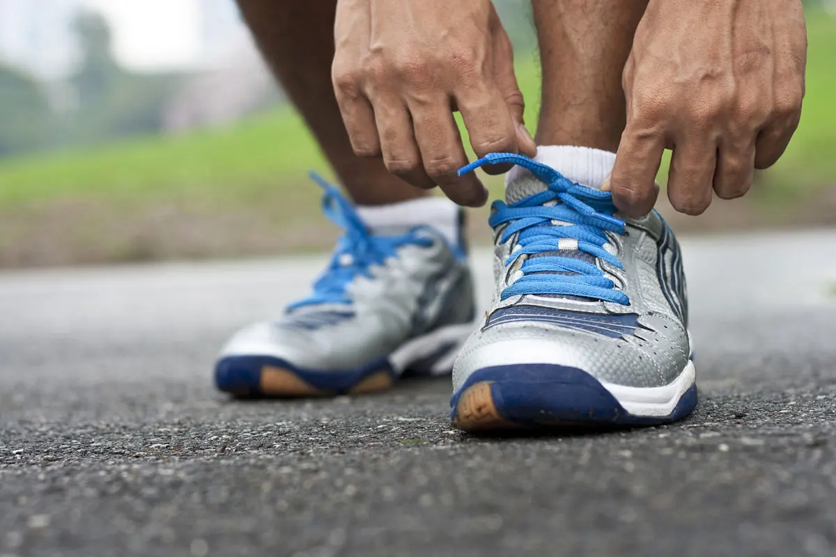 A close up of a runner adjusting their shoes.