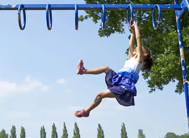 A child hangs from suspended loops on a playground.
