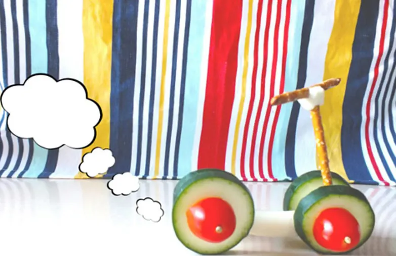 A scooter made from cucubmer and tomato wheels and a pretzel frame.