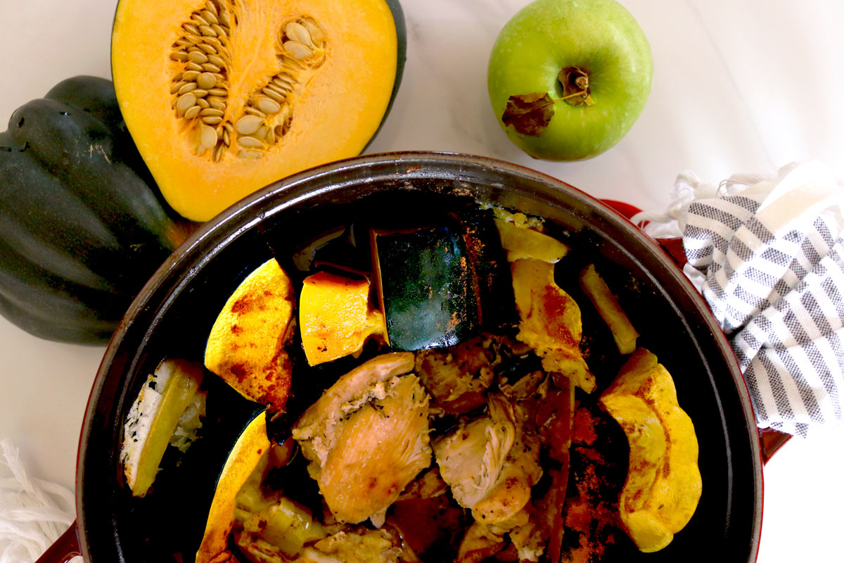 Acorn squash and chicken pieces sit in a large pot