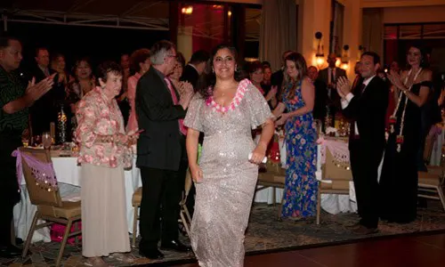 Honoree wearing a sequin gown walks up to the stage to give a speech.