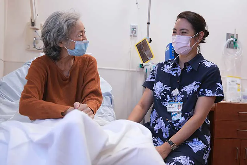 Masked patient and doctor talking in the patient's room.