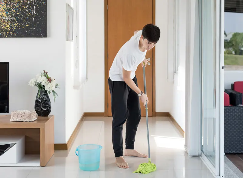 A person mops a floor in a home.
