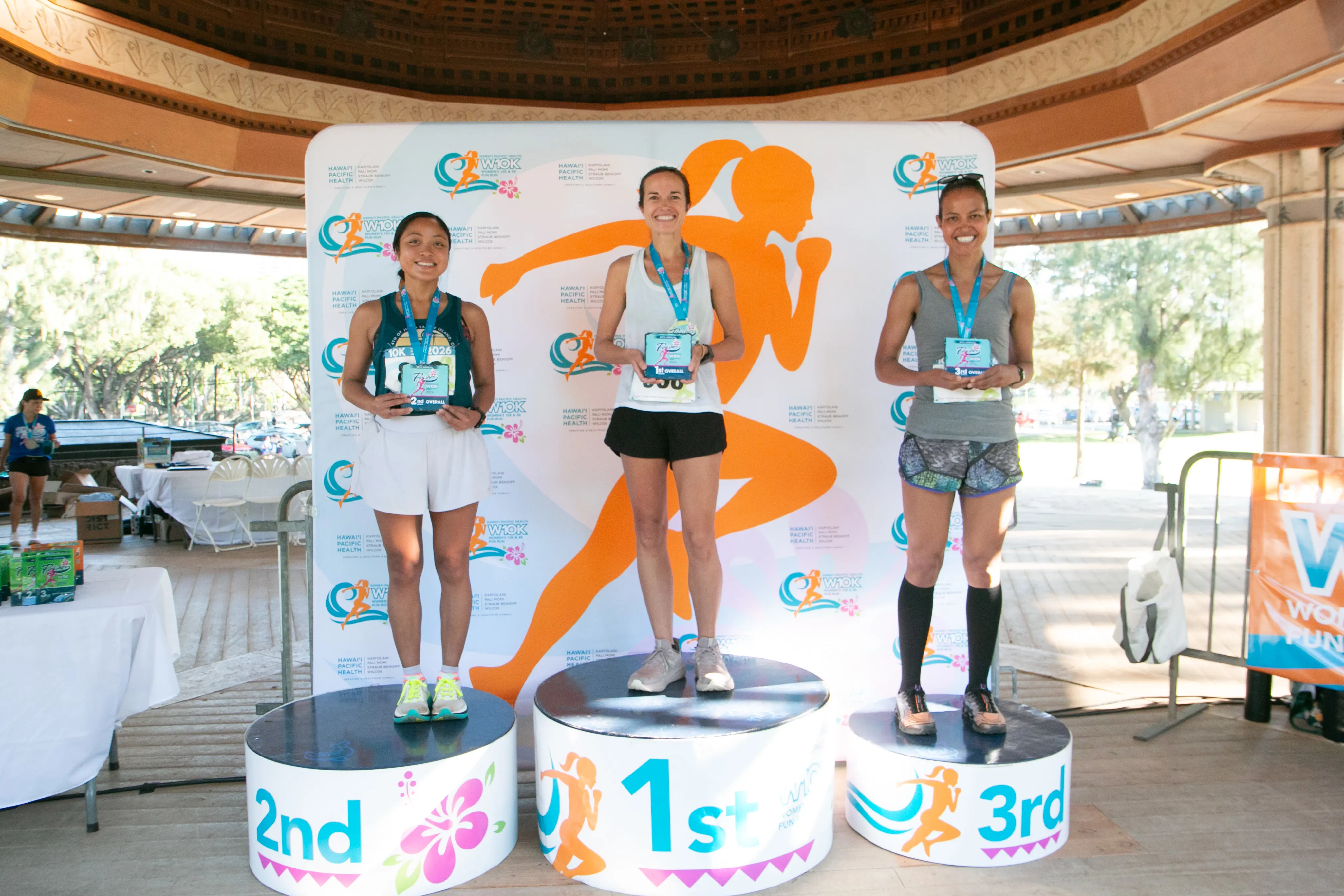 Top three 10K race finishers standing on their respective winner podiums.