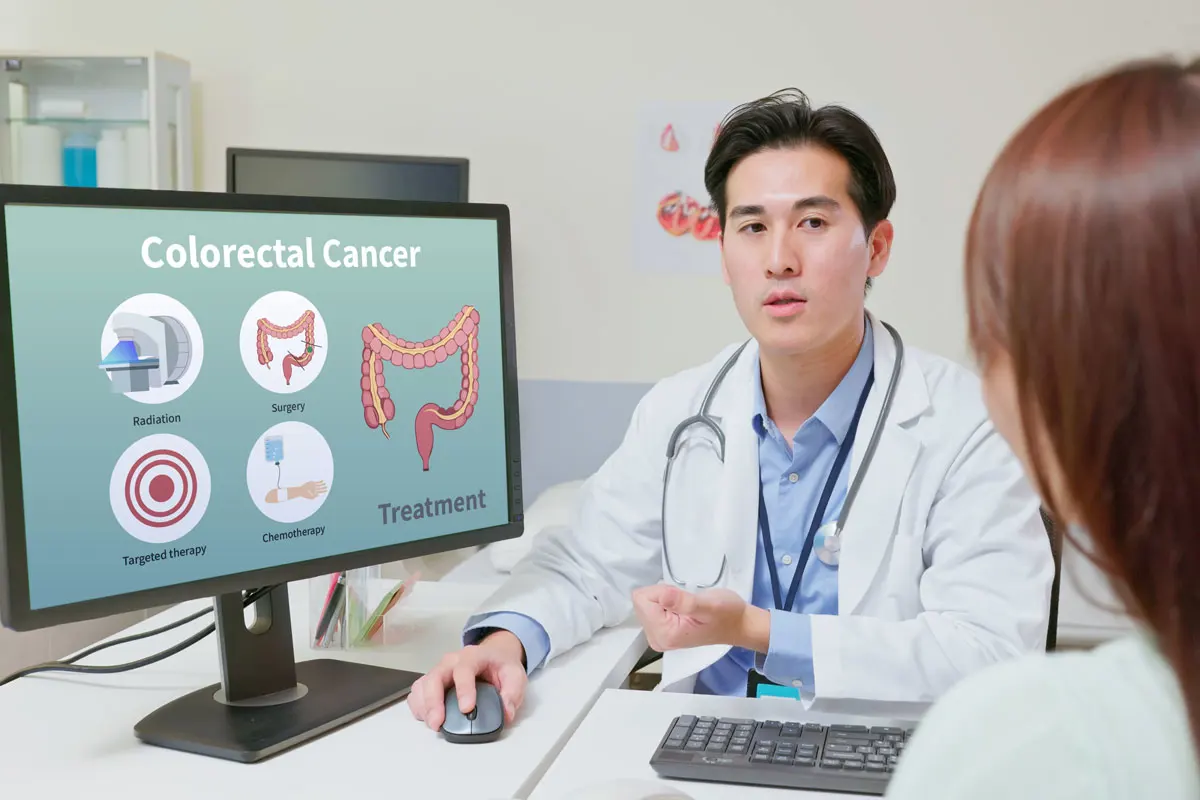 a doctor talks with a young female patient about colorectal screening in an exam room