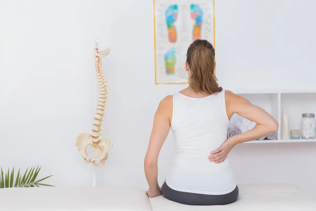 A woman clutching her sore back in a medical office.