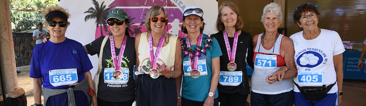 Seven original event participants smile at the camera wearing race bibs.