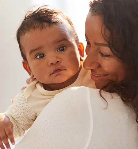 Curious baby looking at the camera while being held by young woman.