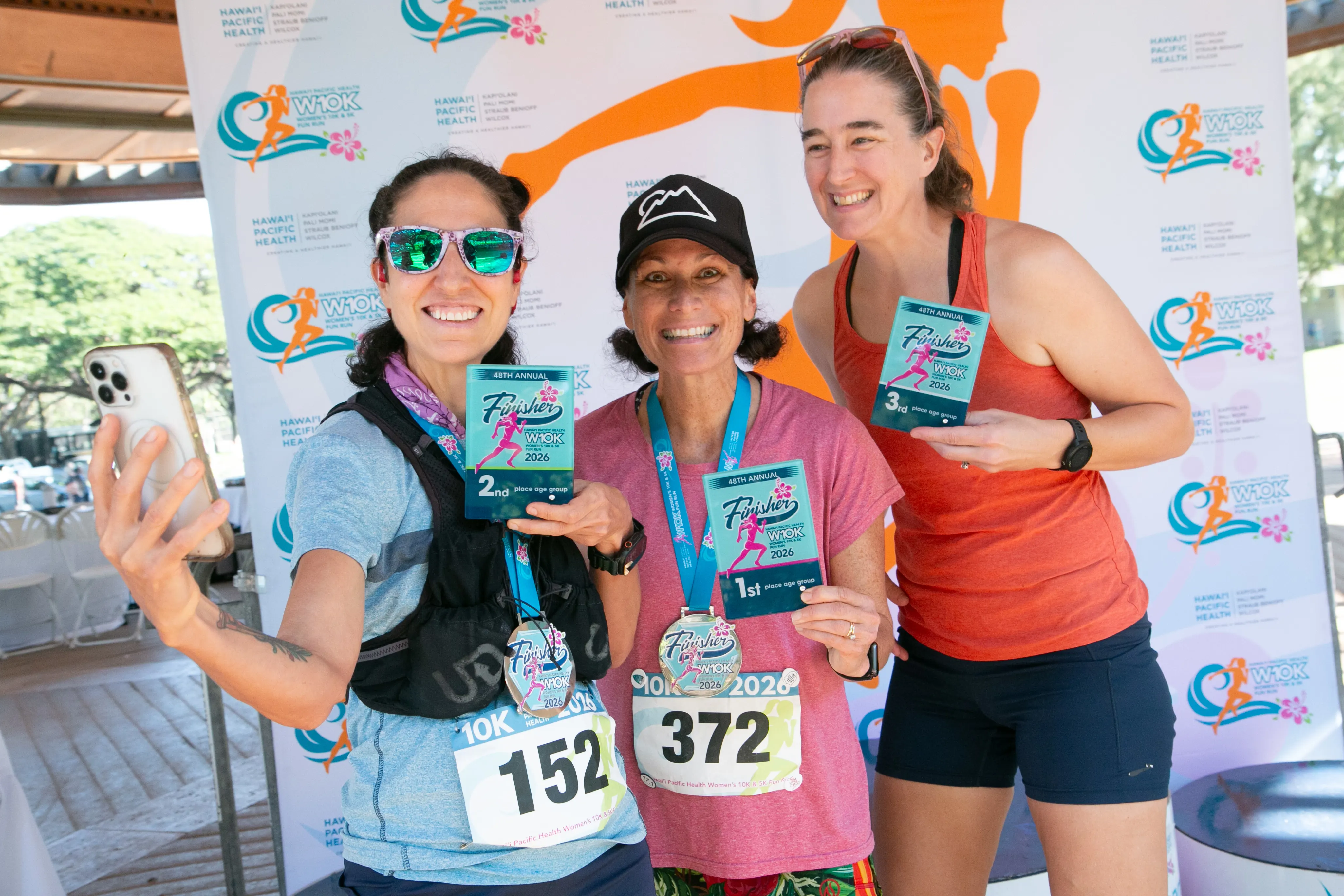 10K age division winners smiling with their medal and awards.