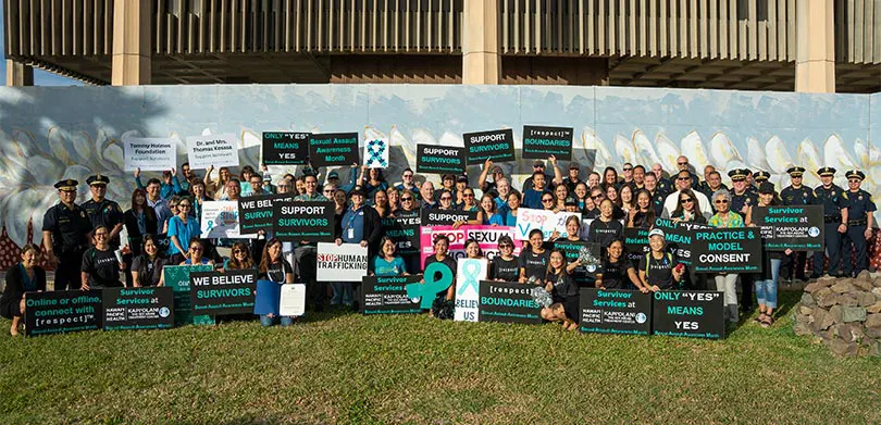 Large group of people holding signs about sexual assault awareness.