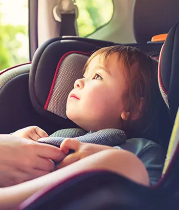 Little child being buckled into car seat.