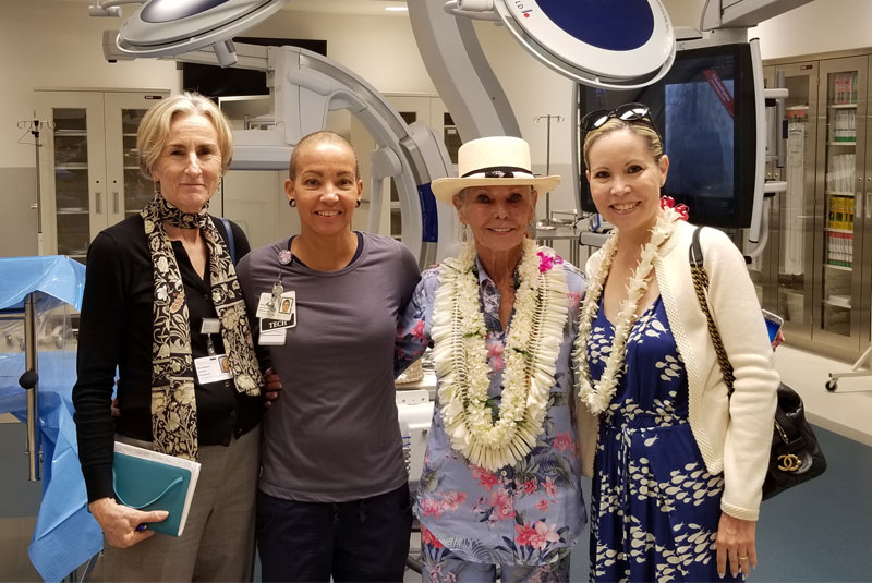 Four people smile at the camera in a medical bay. 