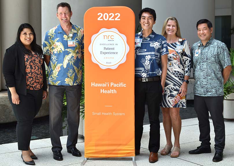 Group posing with the patient experience award pop-up banner.