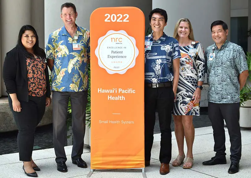 Group posing with the patient experience award pop-up banner.